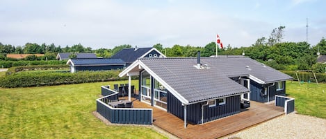 A modern house with a large deck, a covered outdoor area, and a flag.