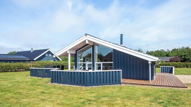 Une maison moderne dotée d’une grande baie vitrée, d’une terrasse en bois et d’une cour clôturée.