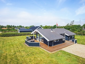 A modern house with a large deck, a covered outdoor area, and a flag on the roof. - 4 Star Holiday Home in Tarm (Tarm)