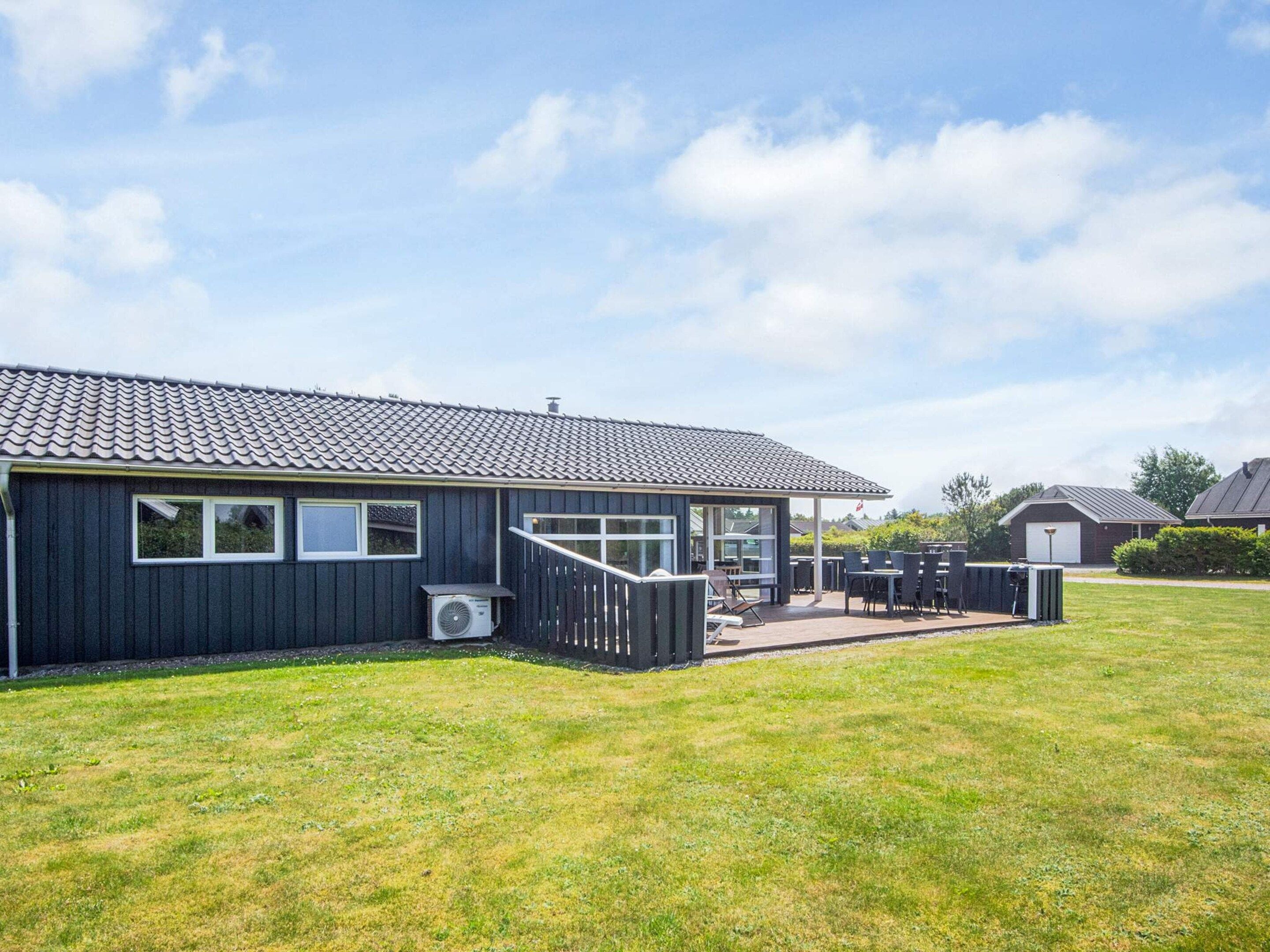 Een modern gebouw met een overdekte patio, zitplaatsen buiten en een gazon.