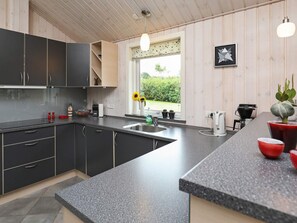 A modern kitchen with dark cabinets, a granite countertop, and a window with a view of greenery.