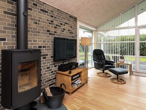 A modern living room with a fireplace, a flat-screen TV, a comfortable leather chair, and a wooden floor.