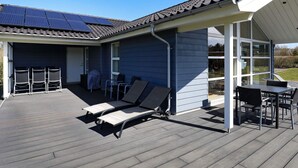 A covered outdoor area with a patio, lounge chairs, and a table. - 5 Star Holiday Home in Fjerritslev (Fjerritslev)