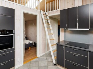 A compact kitchen with built-in appliances, a ladder, and a small sleeping area. - 5 Star Holiday Home in Fjerritslev (Fjerritslev)