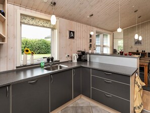 A modern kitchen with a central island, dark cabinetry, and pendant lighting.
