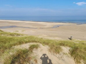 A beach with sand dunes and a clear view of the ocean.
