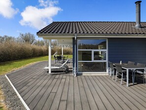 A covered outdoor deck with a dining table and chairs, a grill, and a chimney.