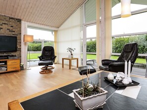 A modern living room with a flat-screen TV, leather chairs, a coffee table, and a potted plant. - 5 Star Holiday Home in Fjerritslev (Fjerritslev)
