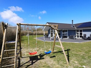 A wooden swing set in a backyard with a house in the background. - 5 Star Holiday Home in Fjerritslev (Fjerritslev)