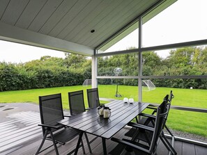An outdoor patio with a table and chairs, a view of a grassy area with a basketball hoop, and a covered roof structure. - 5 Star Holiday Home in Fjerritslev (Fjerritslev)