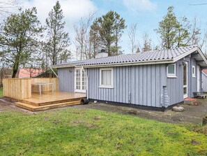 A single-story wooden cabin with a deck, a small attached shed, and a grassy yard. - 6 Person Holiday Home in Oksbol (Oksbol)