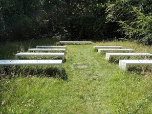 Une zone herbeuse avec des bancs blancs disposés en demi-cercle.