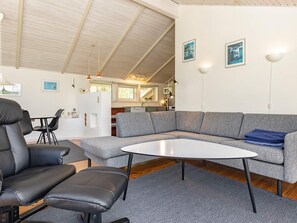 A modern living room with a sectional sofa, a black leather chair, and a small white table. - 5 Star Holiday Home in Laeso (Læsø)