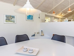 A conference room with a white table, two chairs, a white ceiling, and wall-mounted artwork.