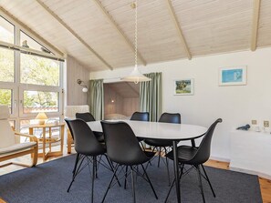 A dining area with a round table, black chairs, and a ceiling with wooden beams.