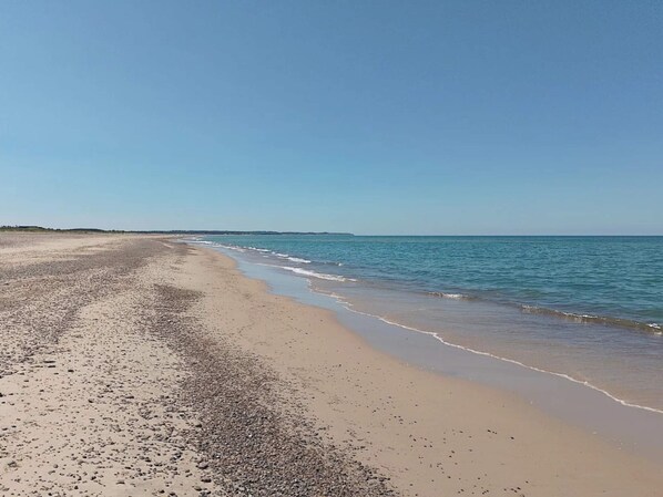 A beach with a wide sandy shore and calm sea.