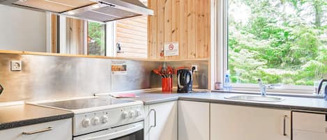 A modern kitchen with a stainless steel range, oven, and a large window with a view of greenery.