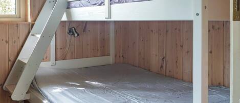 Ein Stockbett mit einer Leiter, Holzwänden und einem Fenster.