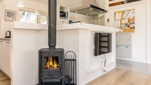 Une cuisine moderne dotée d’un poêle à bois, de meubles blancs et d’un plan de travail noir.