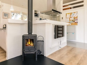 A modern kitchen with a wood-burning stove, white cabinetry, and a black countertop.