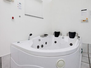 A modern bathroom with a freestanding bathtub, a hand dryer, and a wall-mounted towel rack. - 4 Star Holiday Home in Vaeggerlose (Vaeggerlose)