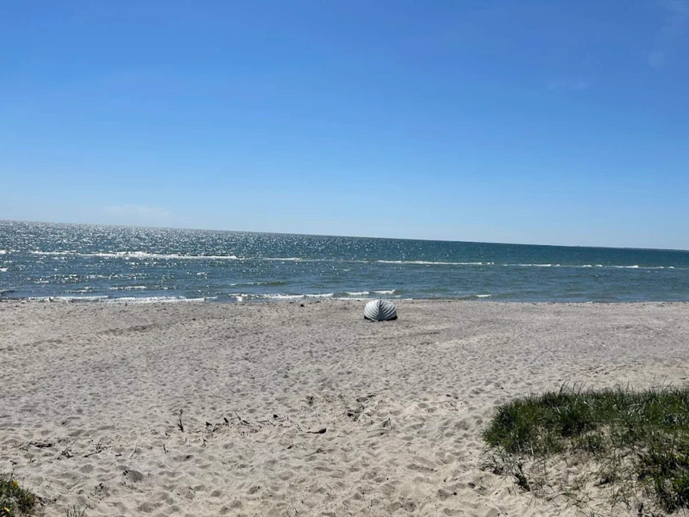 A sandy beach with a clear sky and calm sea.