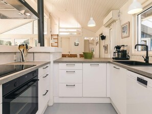 Eine moderne Küche mit weißen Schränken, einem schwarzen Geschirrspüler und einer Kaffeemaschine.