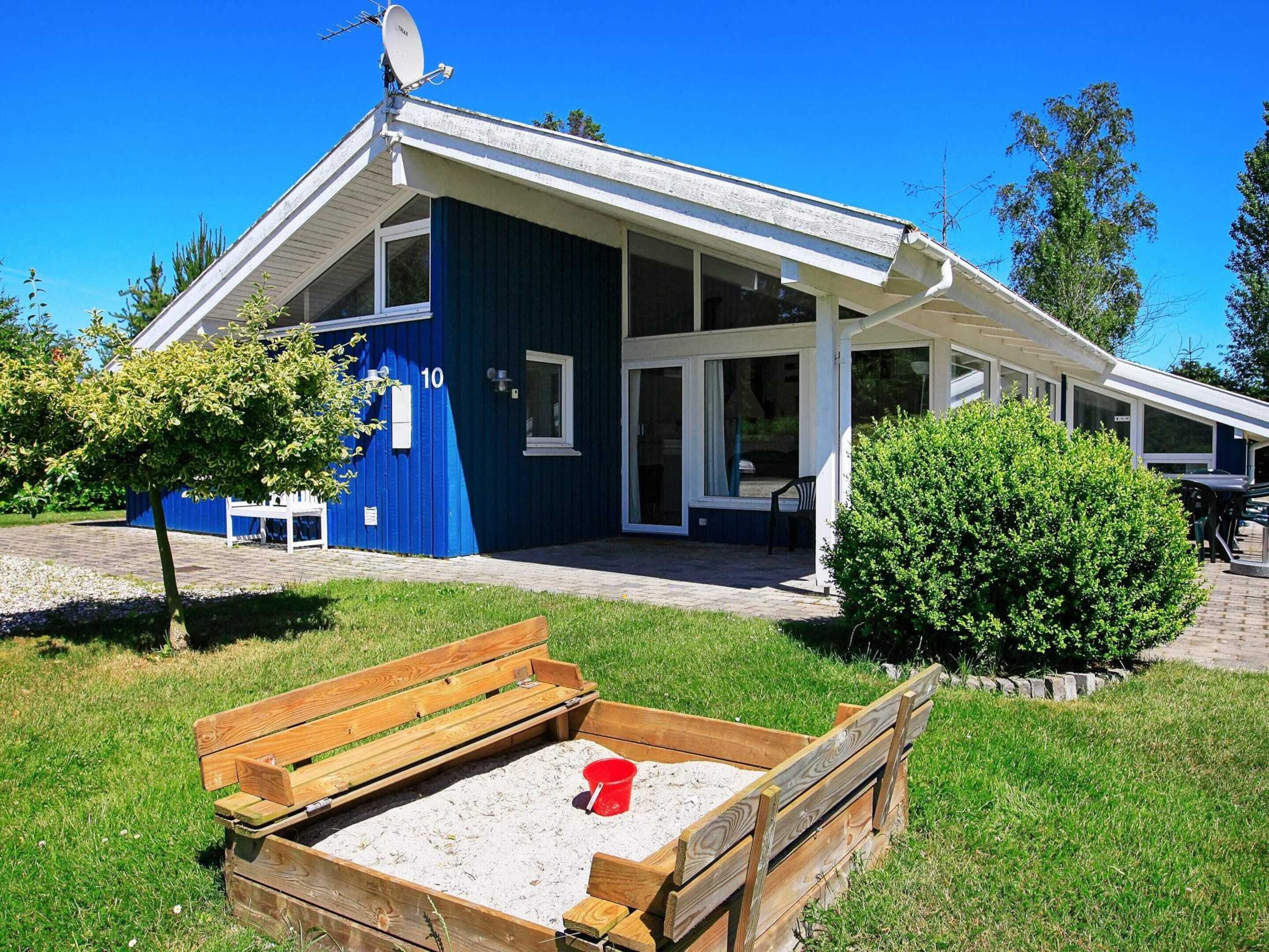 Un bâtiment bleu avec un toit en pente, de grandes fenêtres et un patio couvert.