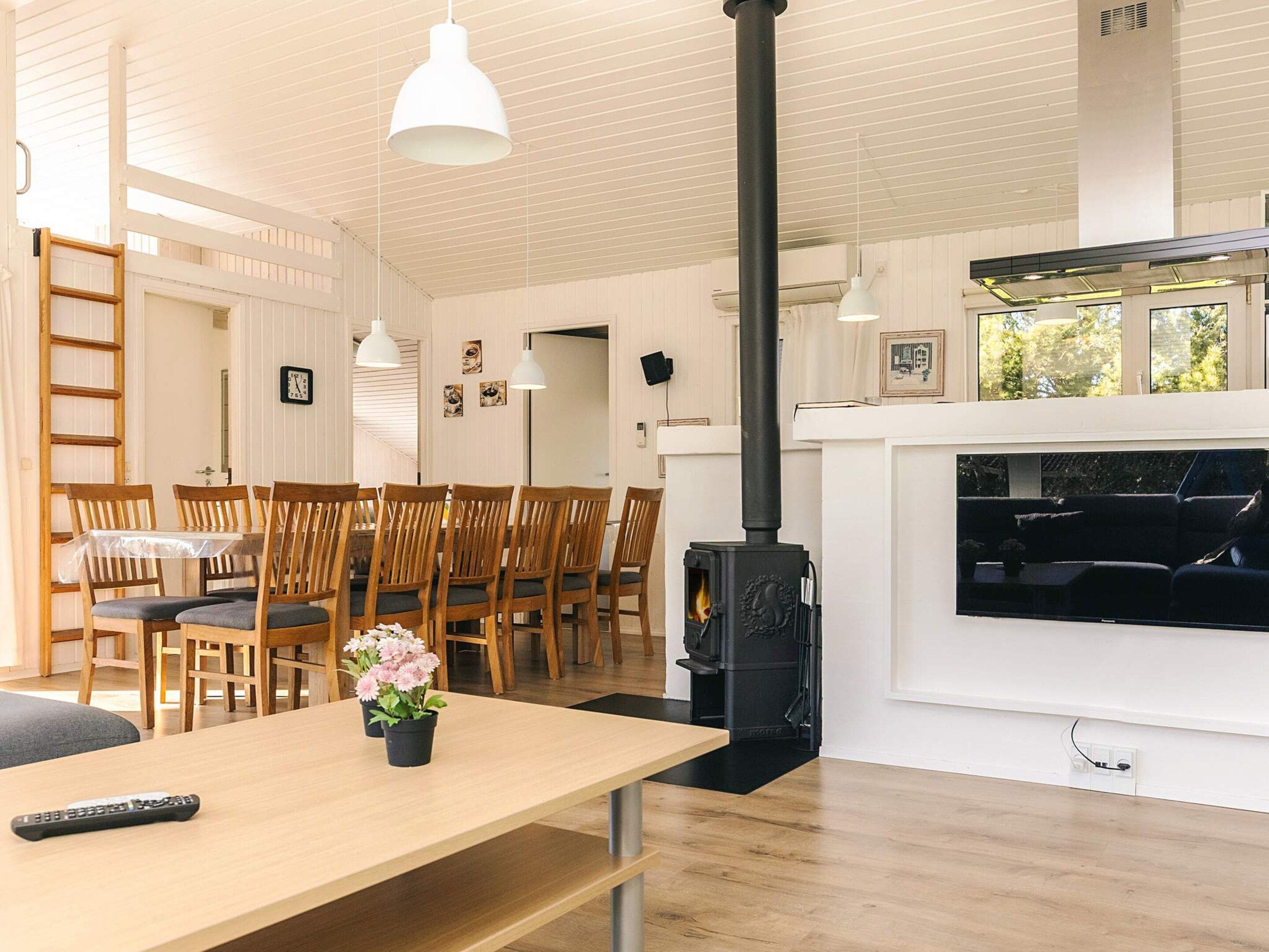 A modern living room with a wooden dining table, chairs, a fireplace, and a TV.