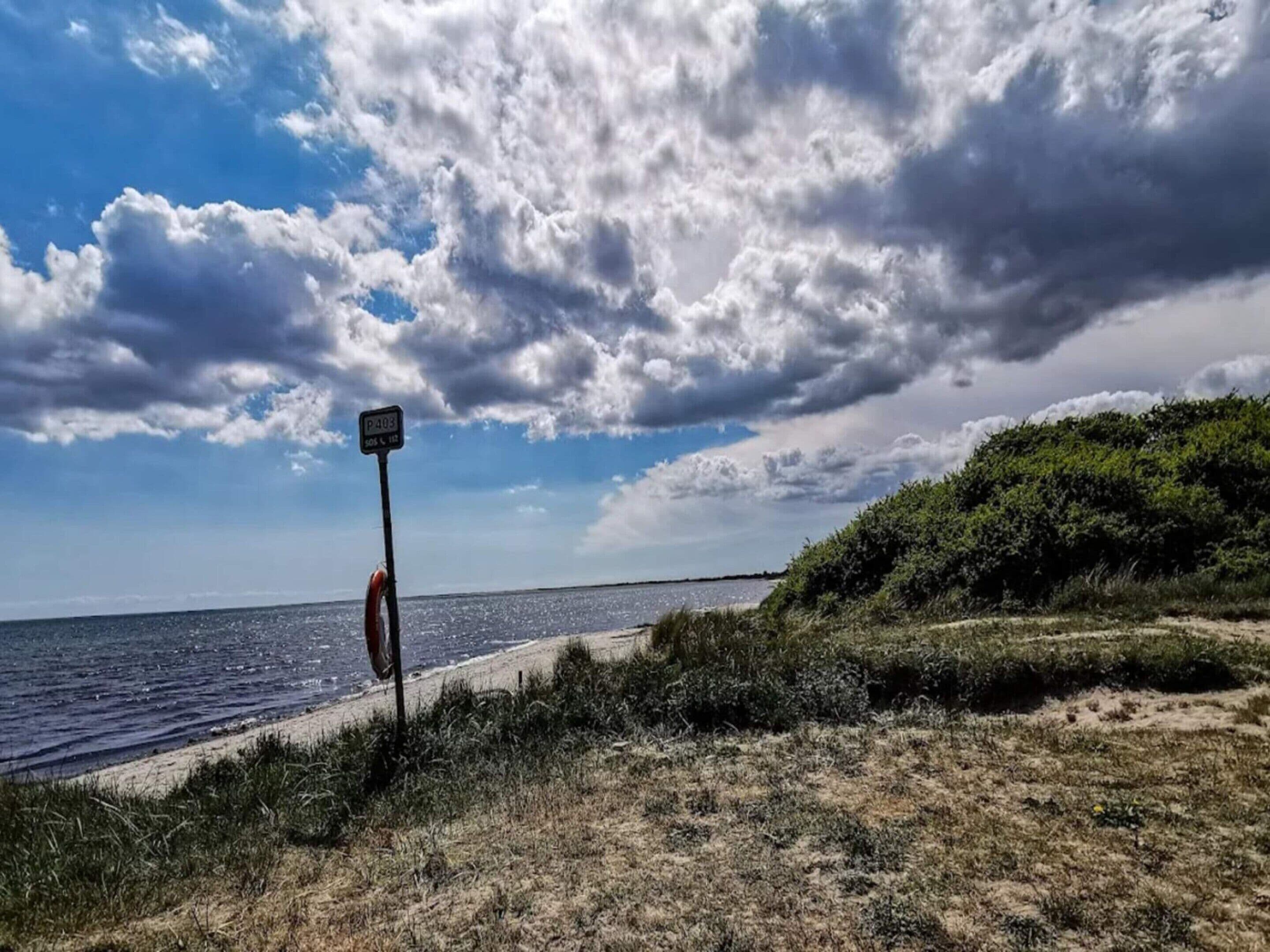 Een strand met een bord, een reddingsboei en een helder uitzicht op de zee.