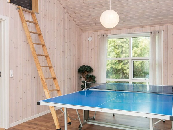 A ping pong table in a room with wooden walls and a window.