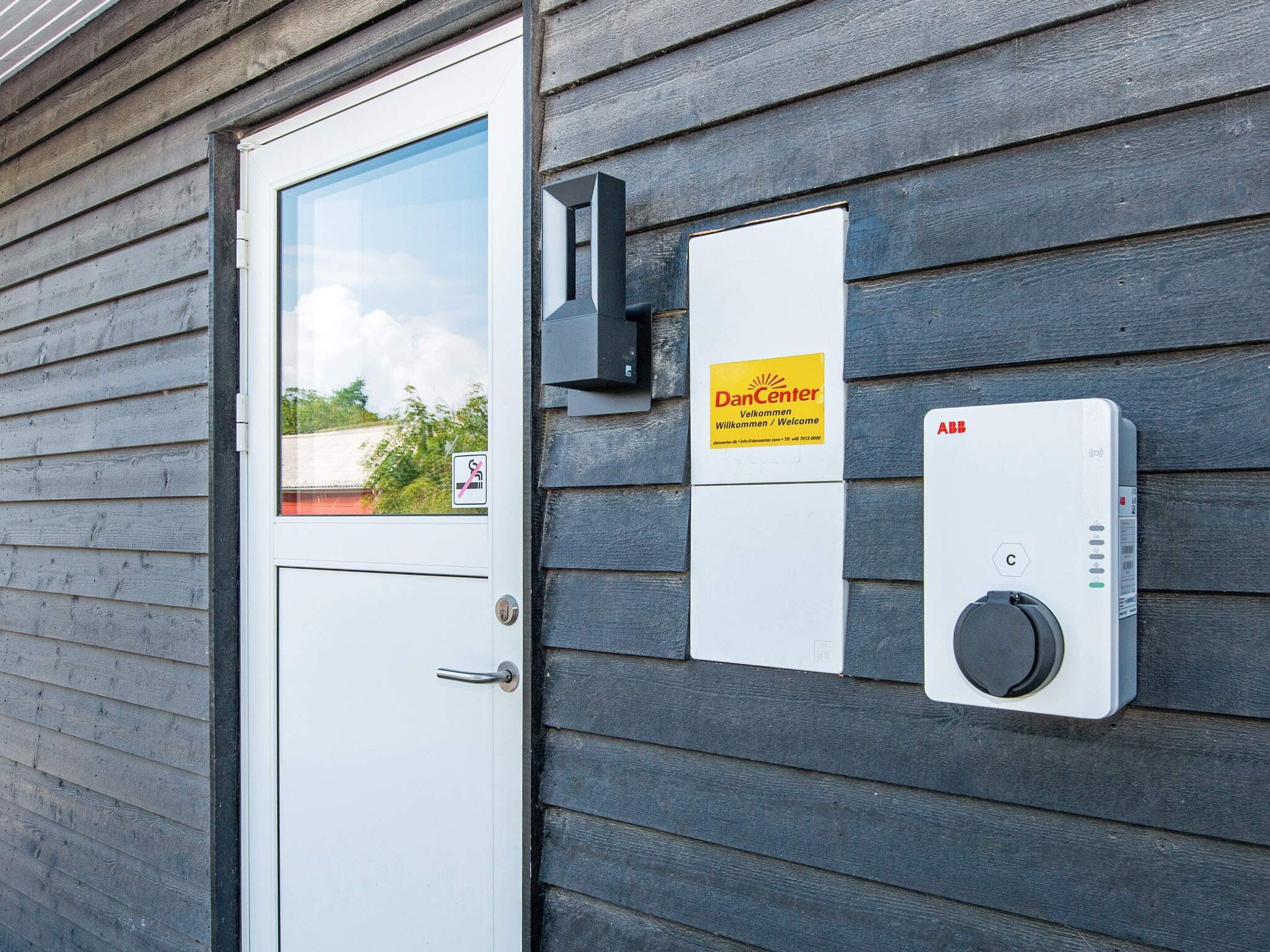 Una puerta con ventana, un cartel de DanCenter y una caja eléctrica ABB en una pared de madera.