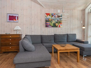 Un salon moderne avec un canapé d’angle, une table basse en bois, une commode et un tableau représentant des montgolfières.