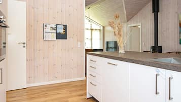 Una cocina moderna con paneles de madera, estufa integrada y piso de madera.