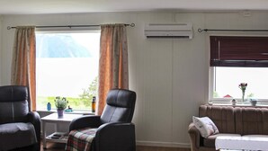A living room with a sofa, two armchairs, a coffee table, and a window with curtains. - 10 Person Holiday Home in Lyngseidet (Lyngen)