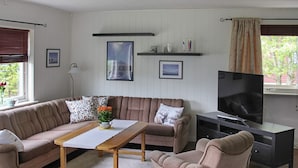 A living room with a sofa, a coffee table, a TV, and a fireplace. - 10 Person Holiday Home in Lyngseidet (Lyngen)