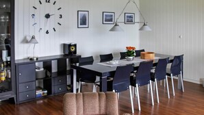 A dining area with a table, chairs, a clock, and a speaker on a cabinet. - 10 Person Holiday Home in Lyngseidet (Lyngen)