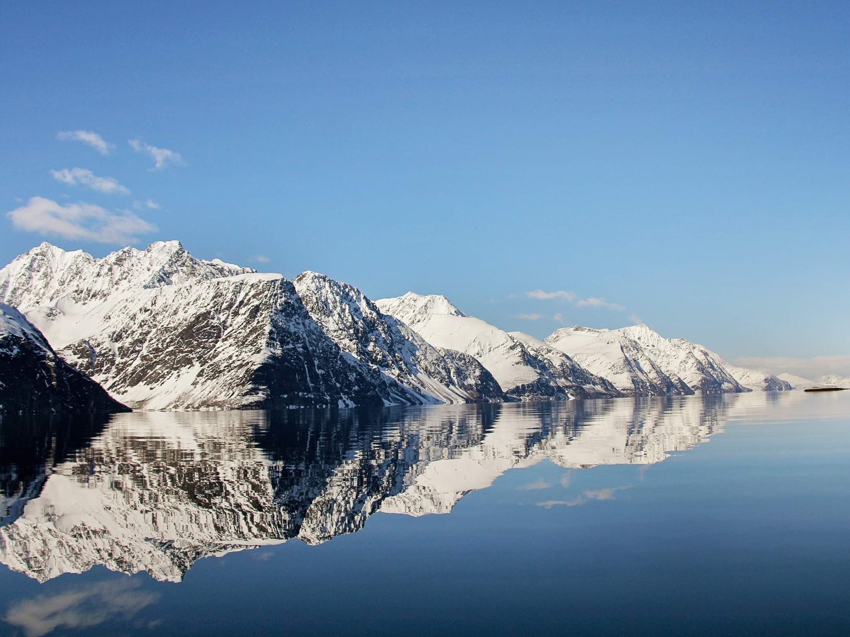 A mountain range reflected in calm water.