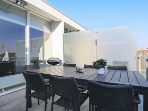 Eine Dachterrasse mit Tisch, Stühlen, einem Blumentopf und einem Grill.