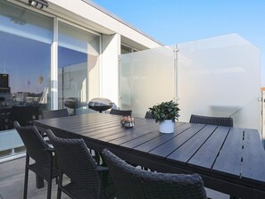 An outdoor dining area with a large table, wicker chairs, and a potted plant.
