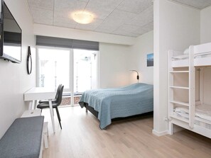 Ein gemütliches Zimmer mit Bett, Schreibtisch und Stuhl. Ein Fenster bietet Blick auf die Stadt.