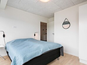 Ein Schlafzimmer mit einem Bett, einem Nachttisch, einem Spiegel und einer Tür zu einem Badezimmer.