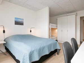 A bedroom with a bed, bedside tables, a desk, and a wardrobe.
