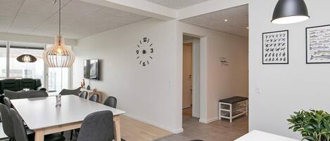 A modern interior with a dining area, a clock on the wall, and a potted plant.