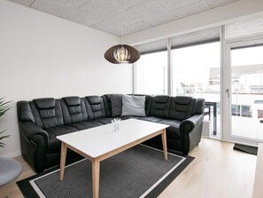 A modern living room with a black leather sofa, a white table, and a black and white rug.