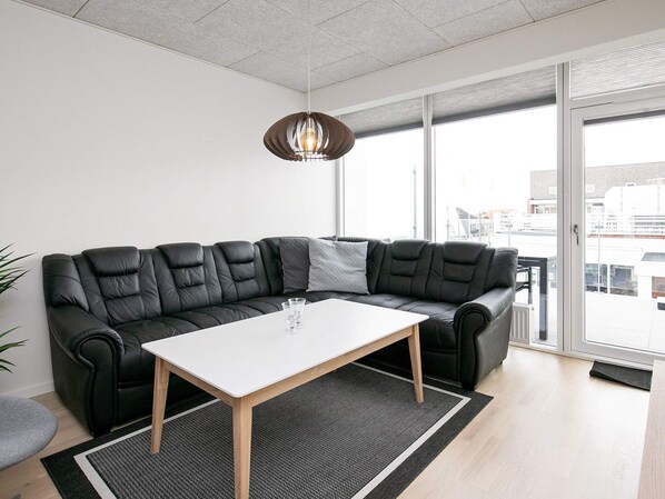 A modern living room with a black leather sofa, a white table, and a black and white rug.