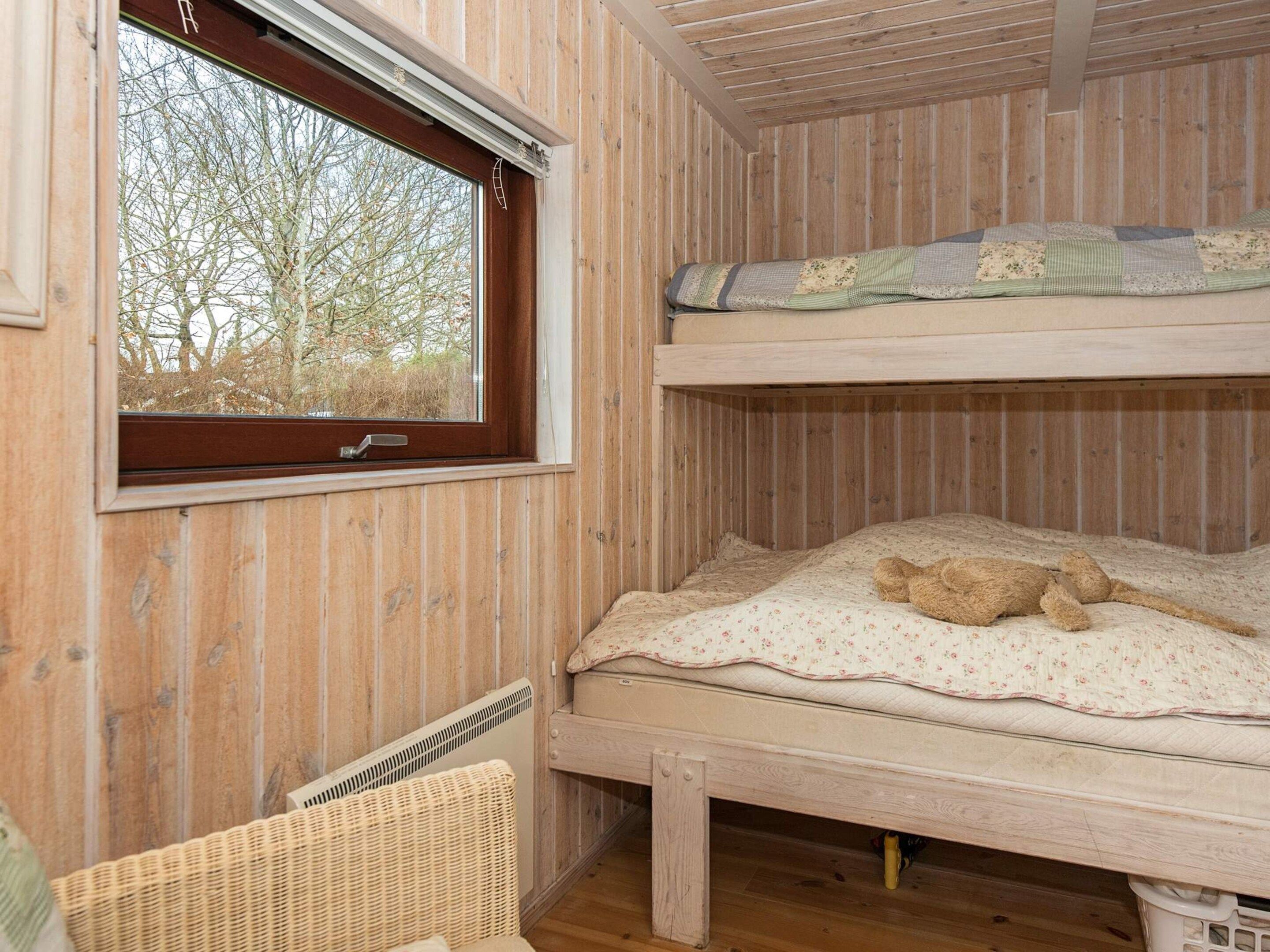Ein Stockbett mit Fenster, ein Korbstuhl und ein Korb.