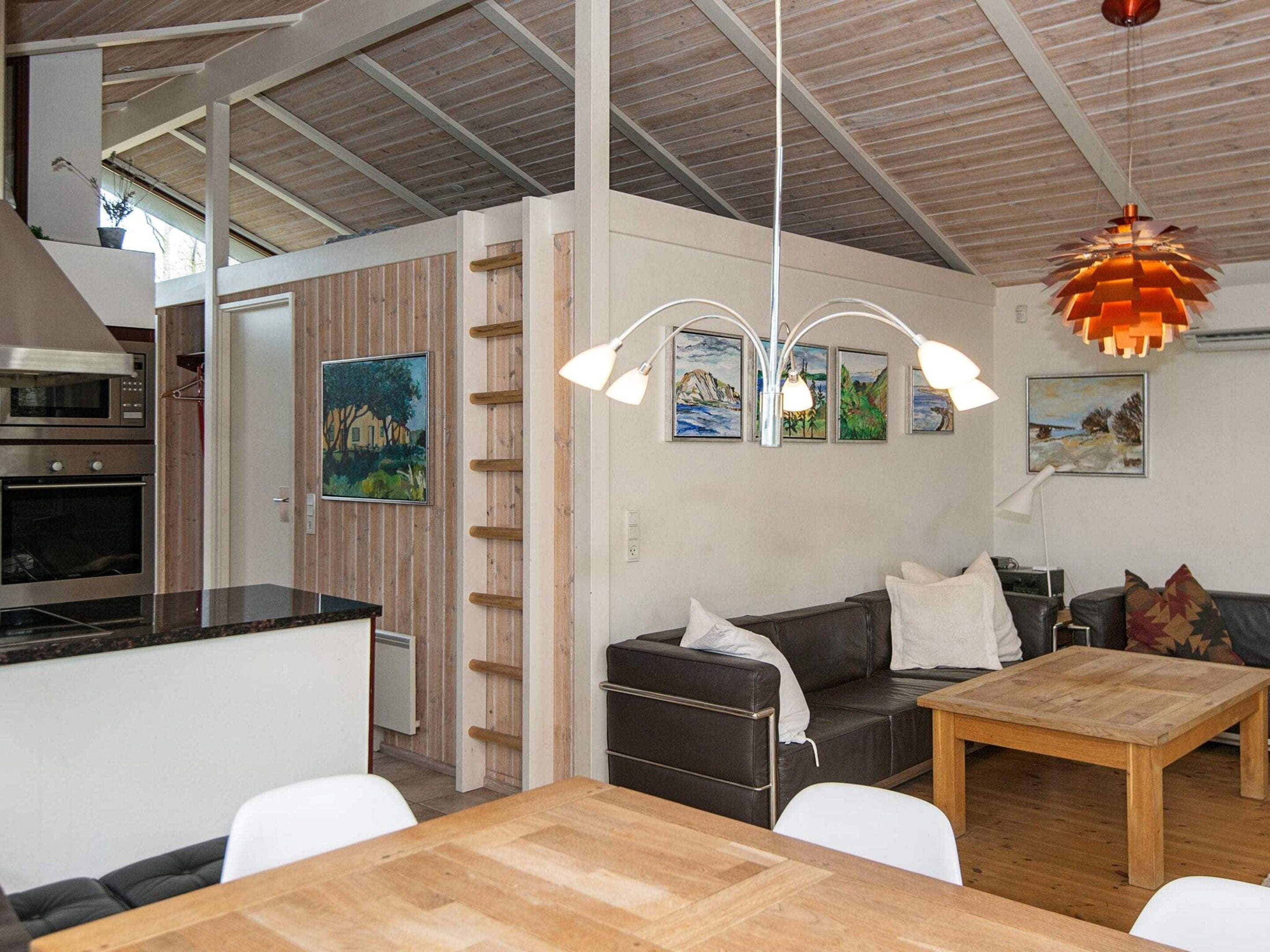 Une cuisine moderne dotée d’appareils électroménagers intégrés, un coin repas avec une table en bois et un espace de vie comprenant un canapé et des œuvres d’art.