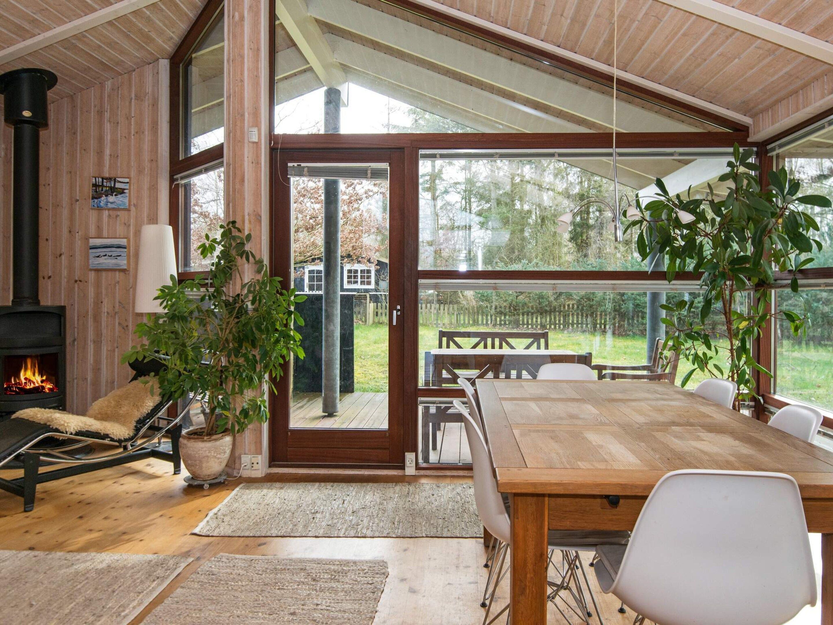 A cozy room with a fireplace, a dining table, and a large window overlooking a garden.