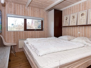 A bedroom with a bed, a window, a chair, and framed botanical prints on the wall. - Holiday Home in Glesborg (Glesborg)